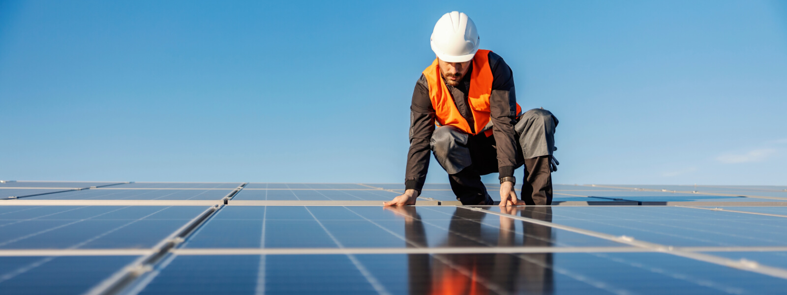 Person checking solar panels on roof