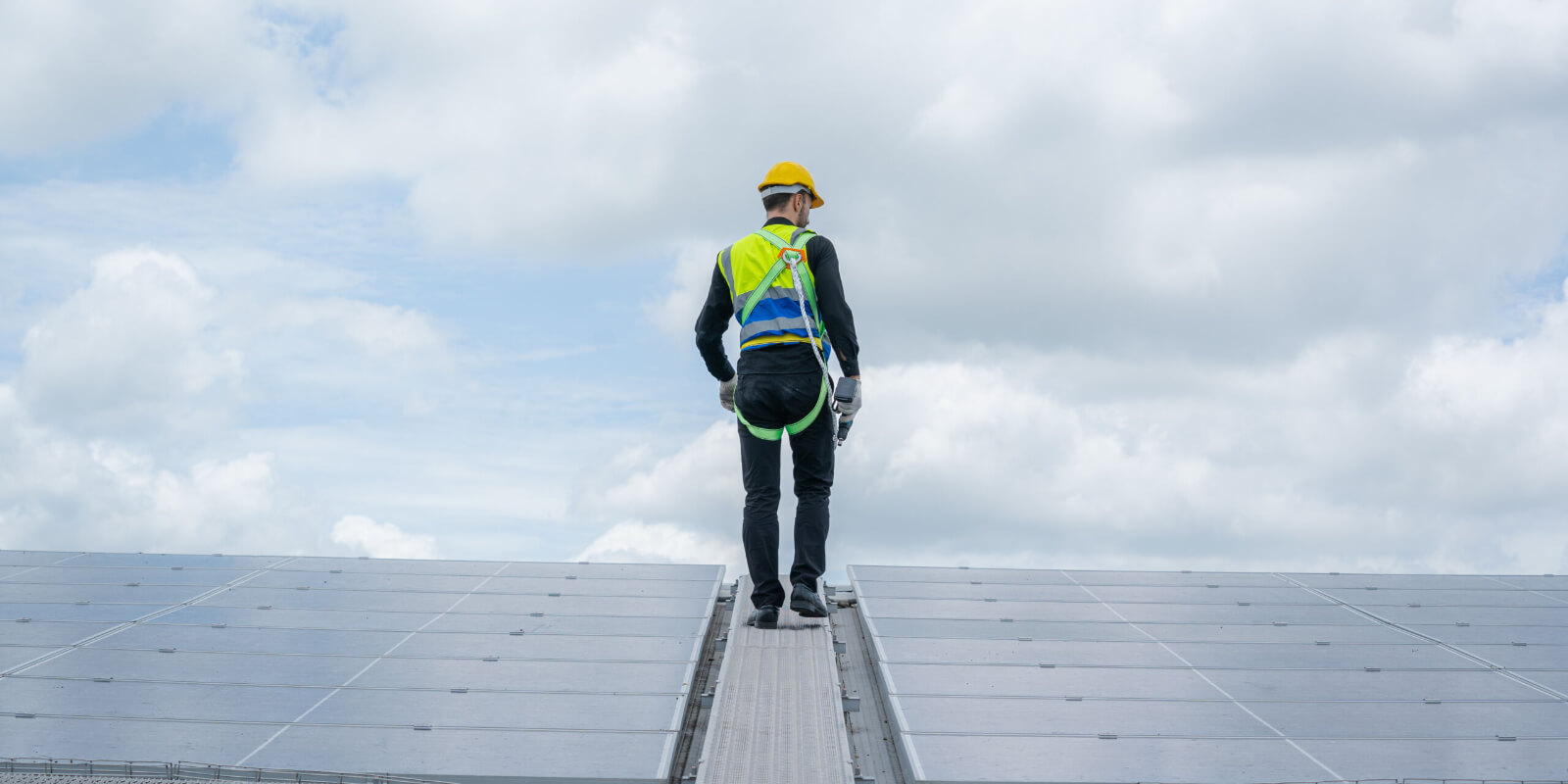 Man standing on roof surrounded by solar panels